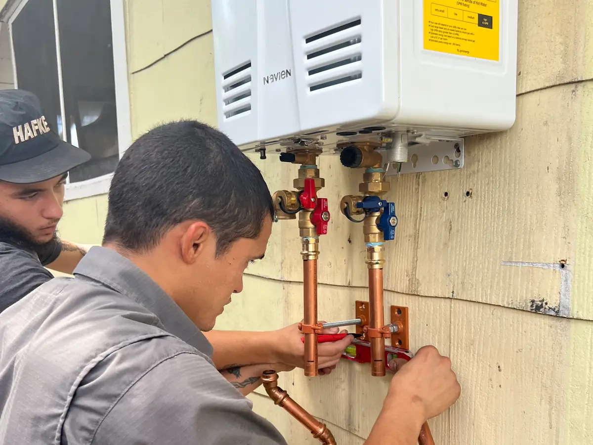 Two Hafke Plumbing technicians installing a tankless water heater